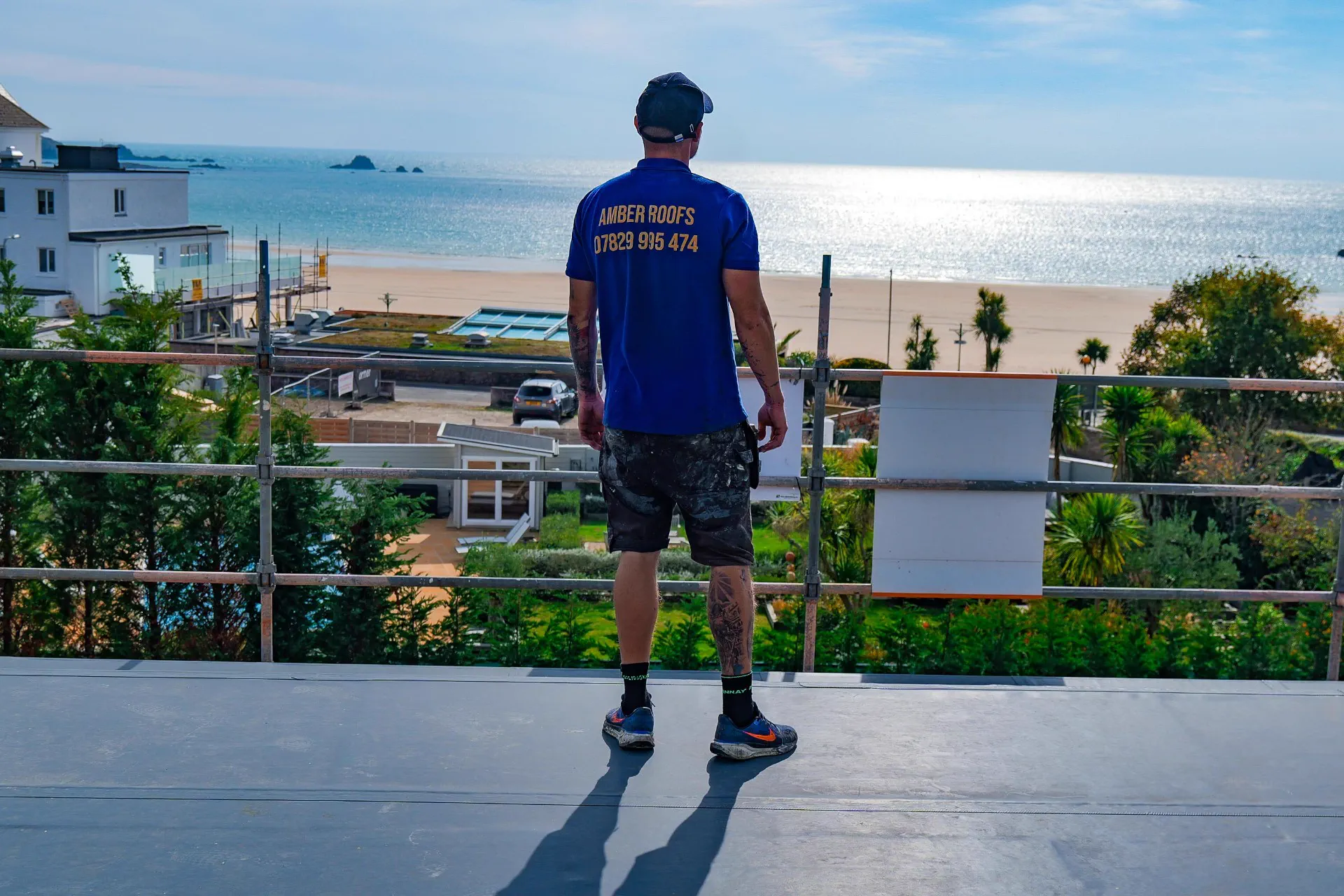 Amber Roofs team member overlooking a Jersey beach from a finished flat roof